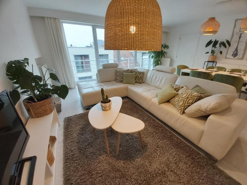 ein Wohnzimmer mit einem weißen Sofa und einem Tisch in der Unterkunft Sea & the City in Blankenberge