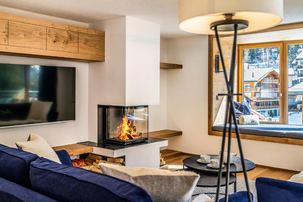 sala de estar con chimenea y sofá azul en Riverside 2nd Floor South, en Saas-Fee