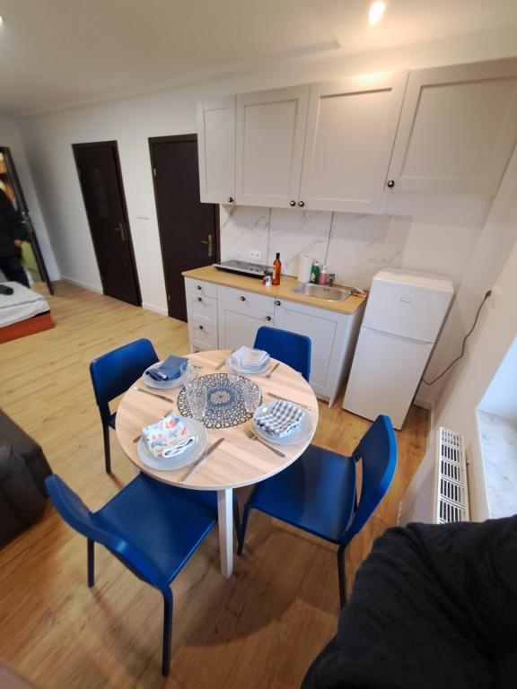 uma cozinha e uma mesa com cadeiras azuis num quarto em Noclegi przy Browarnej em Żyrardów