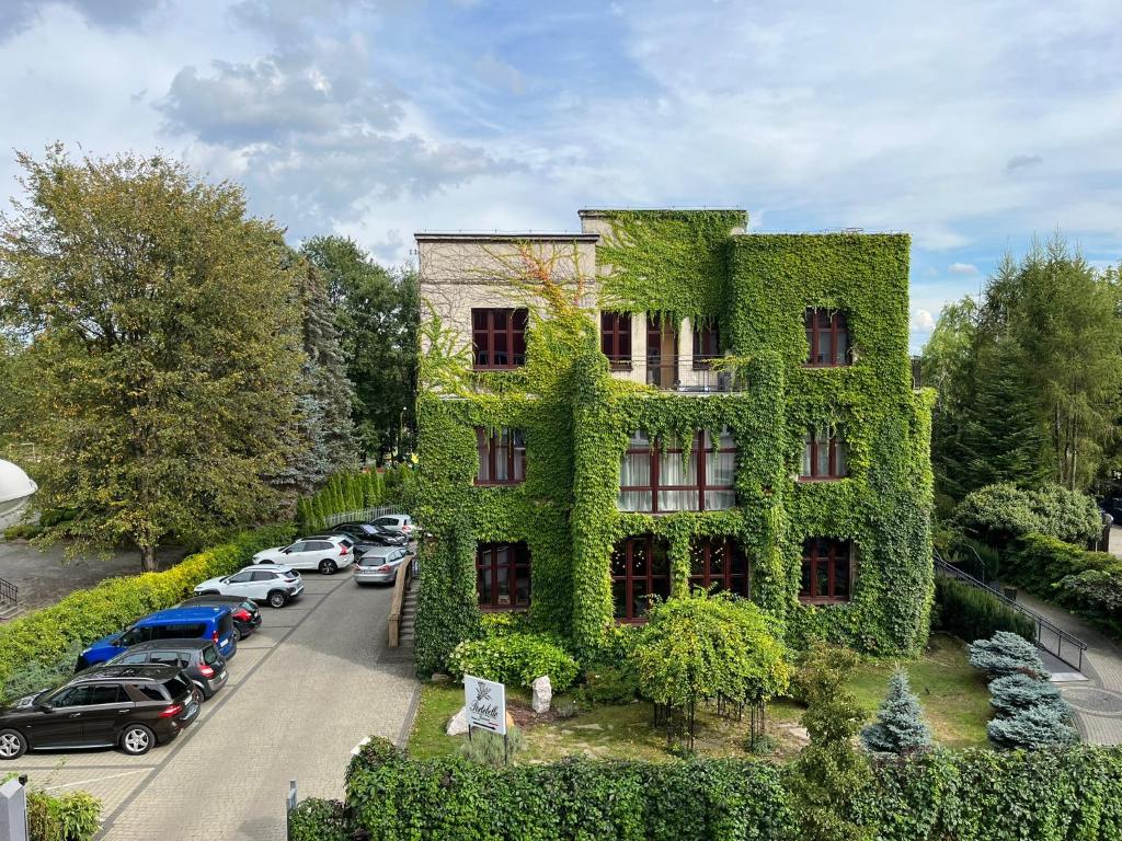 um edifício coberto de hera verde ao lado de um parque de estacionamento em La Bouche Appartements em Oświęcim