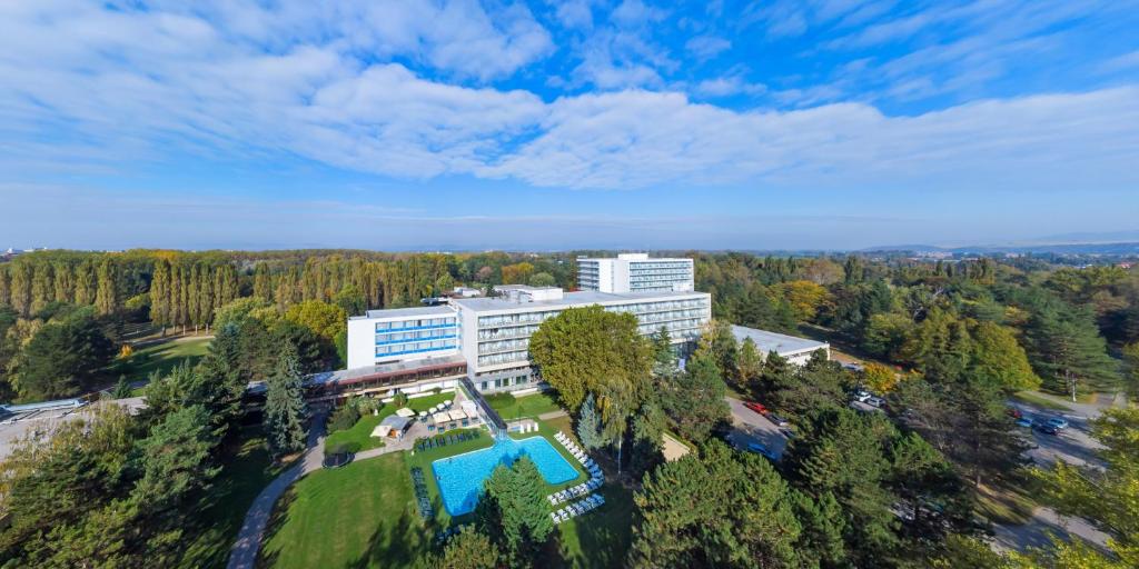 - une vue sur un bâtiment avec une piscine et des arbres dans l'établissement Ensana Splendid, à Piešťany