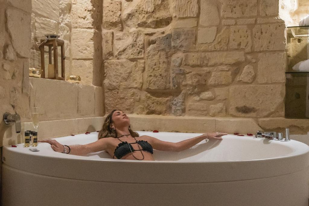 una donna sdraiata in un bagno con vasca di Le Nicchie luxury rooms a Lecce