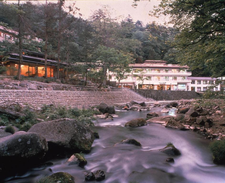 un fiume con rocce di fronte a un edificio di Gensenkan a Nasushiobara