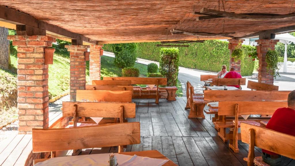 un restaurante con mesas y bancos de madera y personas sentadas en mesas en Hotel & Restaurant Se-Mi, en Veliko Trgovišće