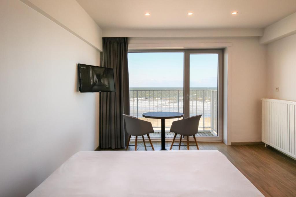 a bedroom with a bed and a table and chairs at Hotel Sandeshoved Zeedijk in Nieuwpoort