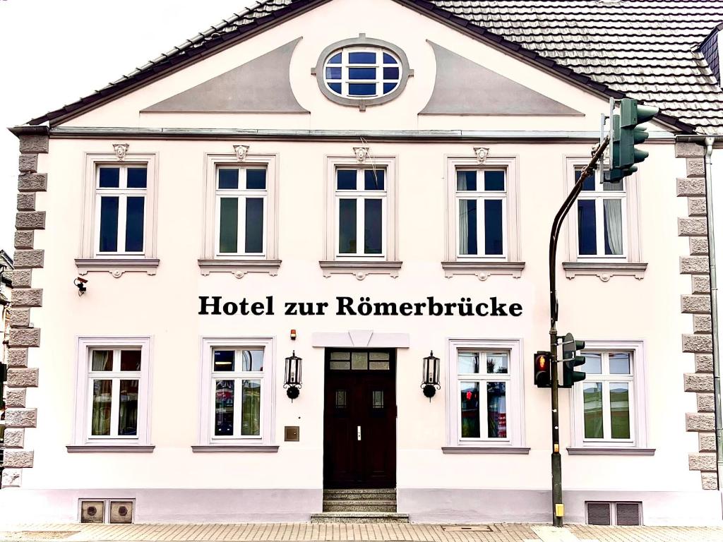 a white building with a black door and a street light at Hotel zur Römerbrücke in Neuwied