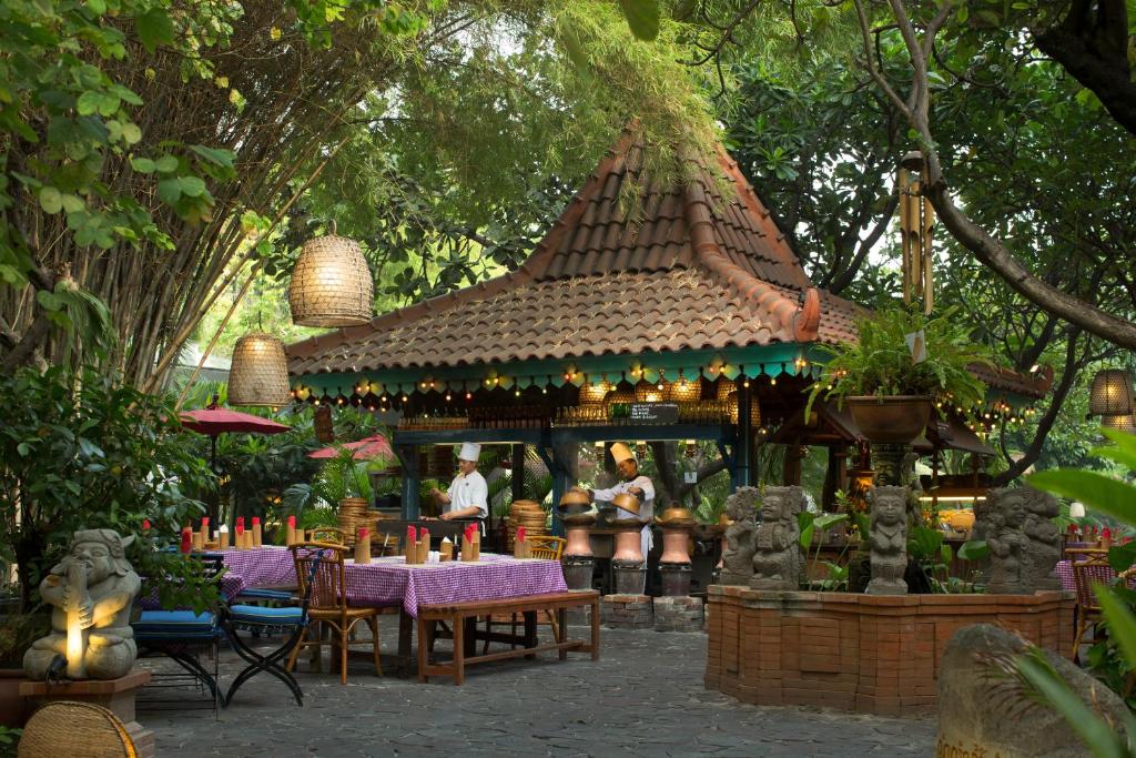 ein Restaurant mit einem Tisch und Stühlen im Garten in der Unterkunft Bumi Surabaya City Resort in Surabaya