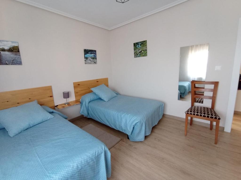 een slaapkamer met 2 bedden en een stoel. bij La Casa del Limonero in Suances