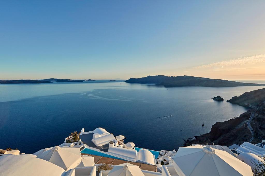 a view of a body of water with white buildings at Katikies Santorini - The Leading Hotels Of The World in Oia