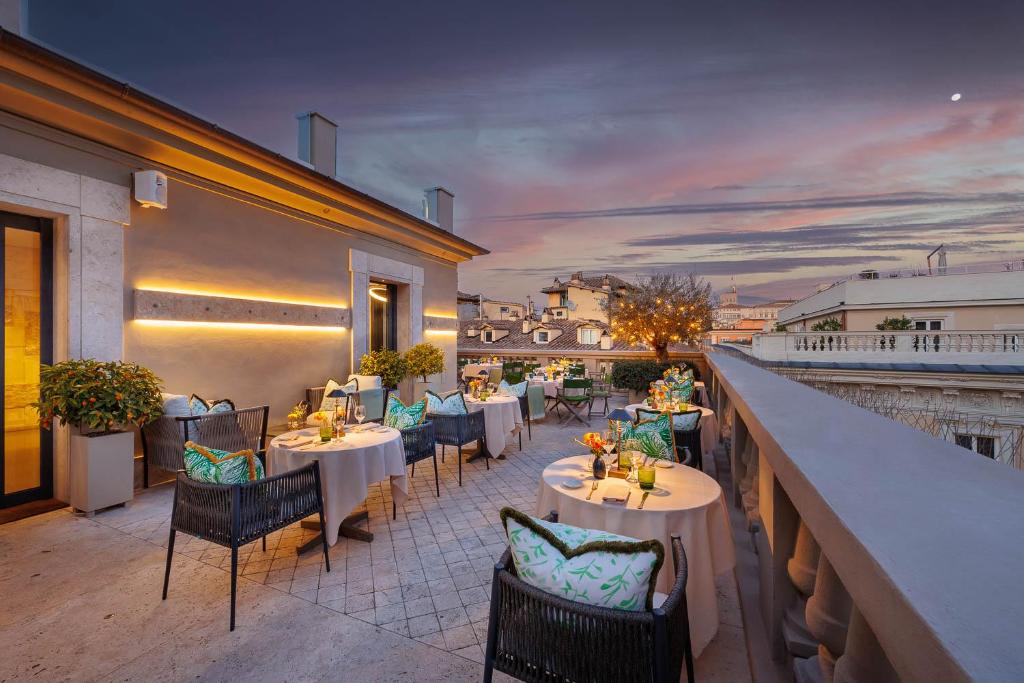 ein Restaurant mit Tischen und Stühlen auf einem Balkon in der Unterkunft Singer Palace Hotel Roma in Rom