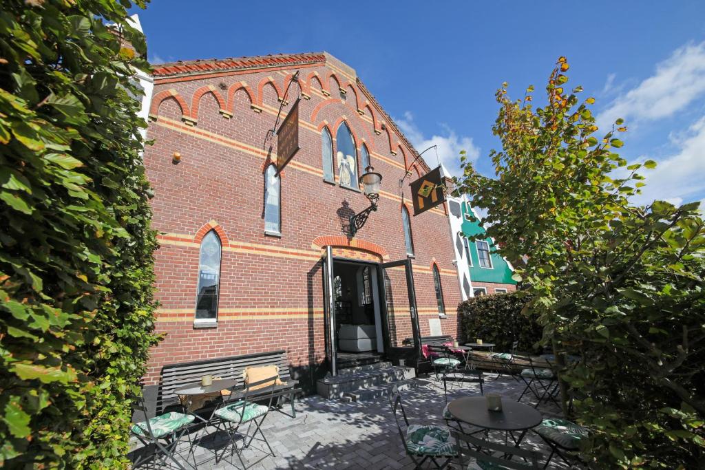 een bakstenen gebouw met tafels en stoelen ervoor bij Valerius Boutique Hotel in Wormer