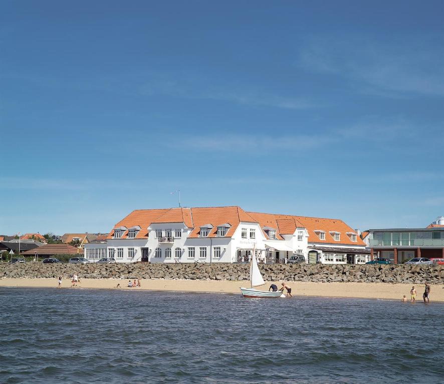 een boot in het water bij een strand met huizen bij Hjerting Badehotel in Esbjerg