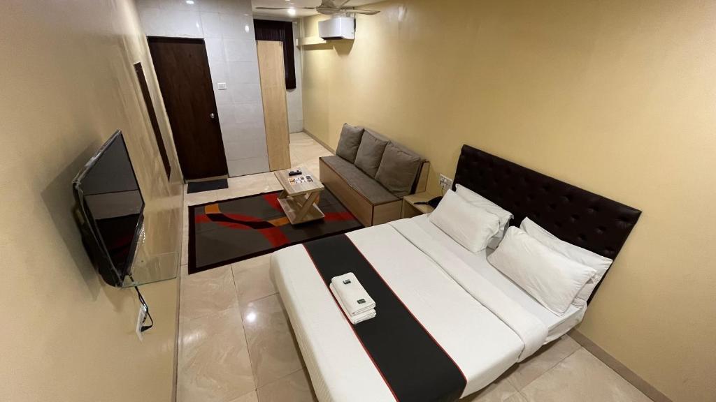 a bedroom with a bed and a couch and a television at U LIFE HOTEL in Mumbai