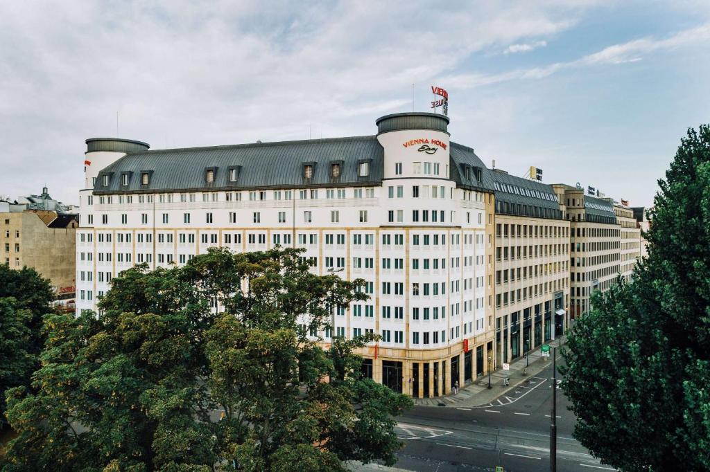 um grande edifício branco com uma bandeira em cima em Vienna House Easy by Wyndham Leipzig em Leipzig