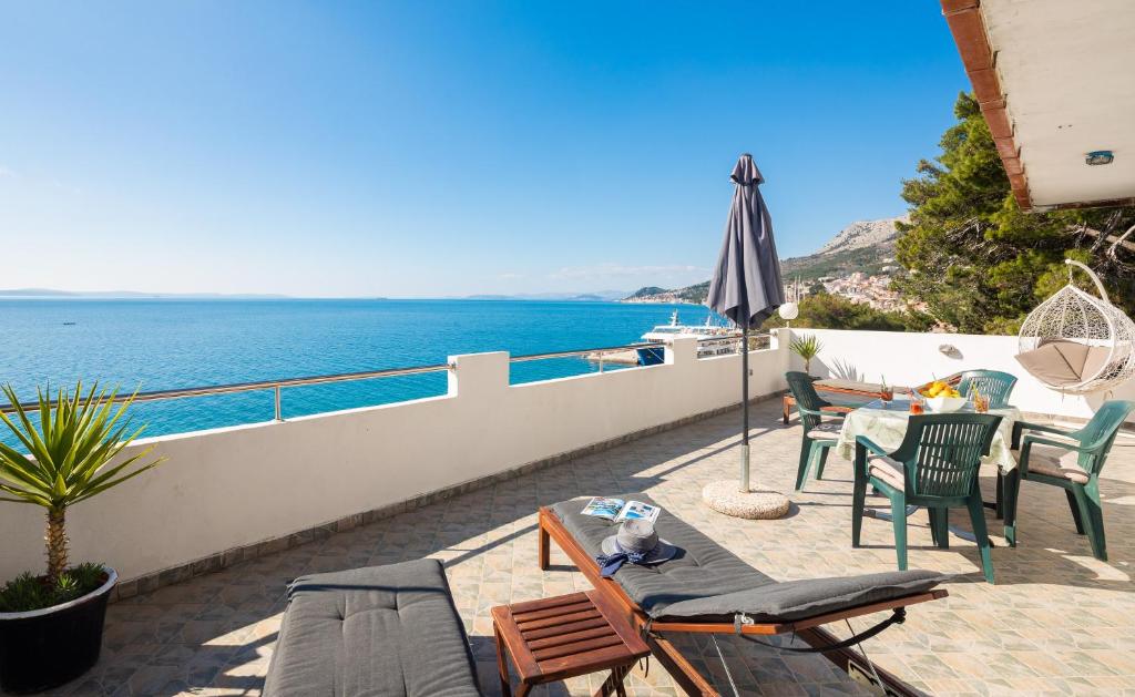 a patio with chairs and an umbrella and the ocean at Sky Way Apartments in Dugi Rat