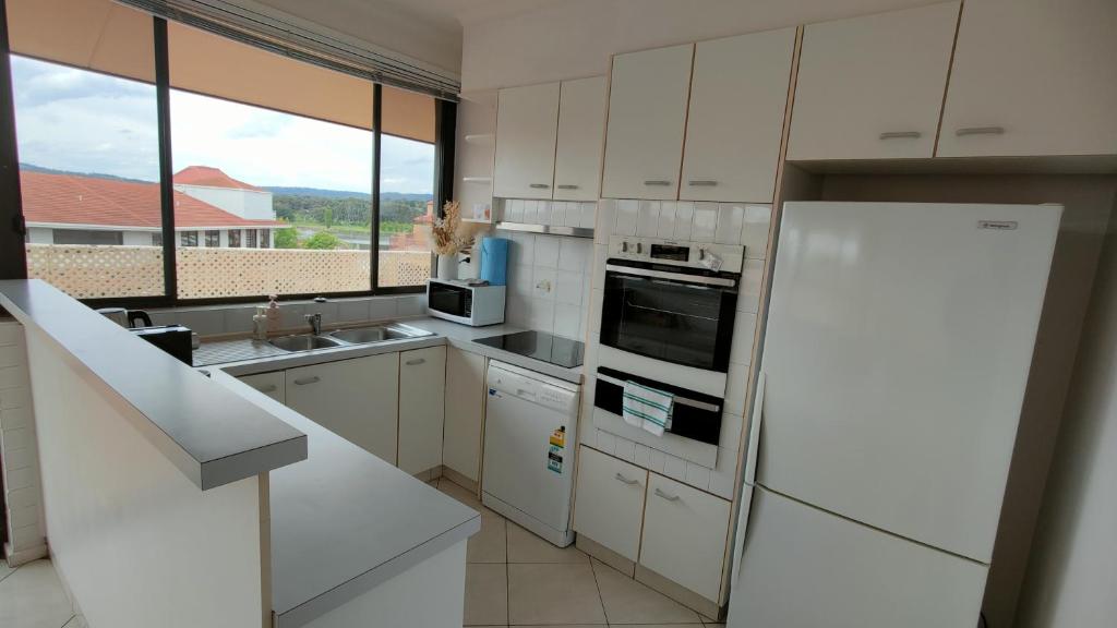 eine Küche mit weißen Geräten und einem großen Fenster in der Unterkunft Tuggeranong Short Stay #07 - Sleeps 6 in Tuggeranong