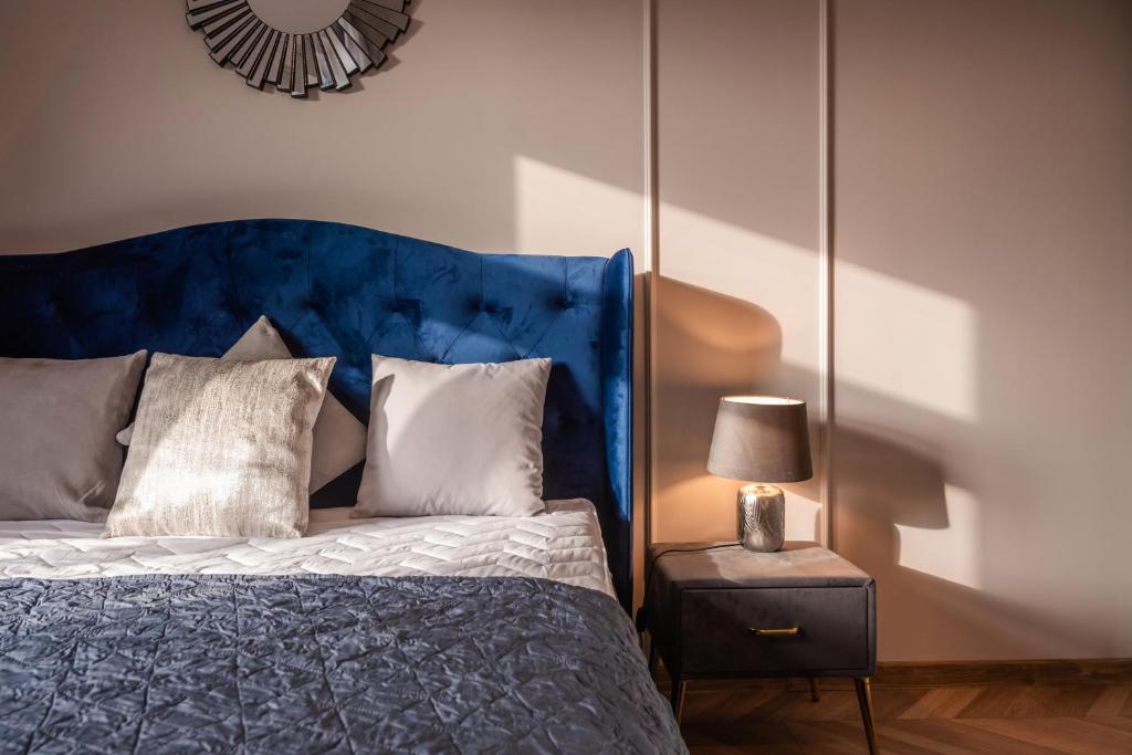 Bett mit blauem Kopfteil und einer Lampe auf dem Tisch in der Unterkunft Apartament Kolegialna 8 in Płock