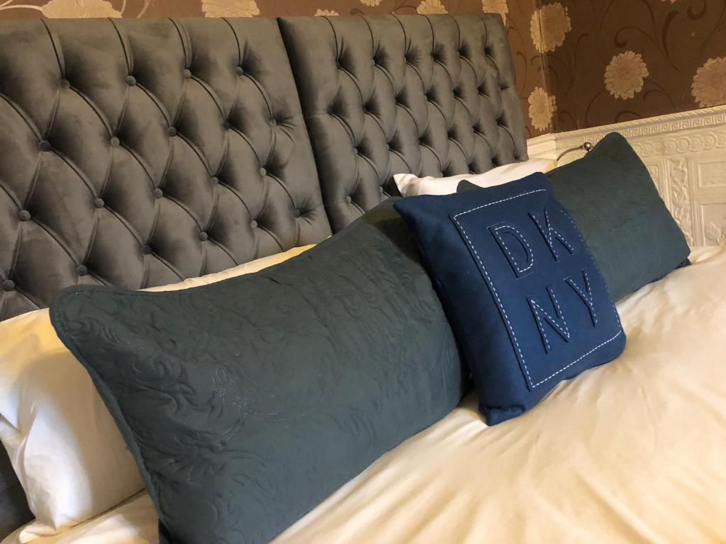 een bed met een zwart hoofdeinde en een blauw kussen bij Ashfield Hotel in Huddersfield