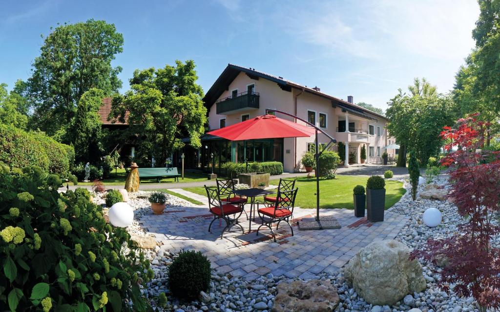 een patio met stoelen en een tafel met een rode parasol bij Landhaus Riedl in Bad Füssing