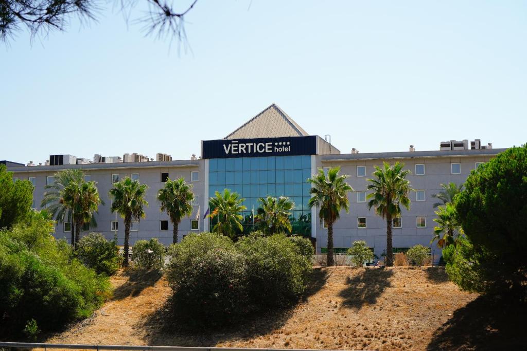 a building with palm trees in front of it at Vértice Sevilla Aljarafe in Bormujos