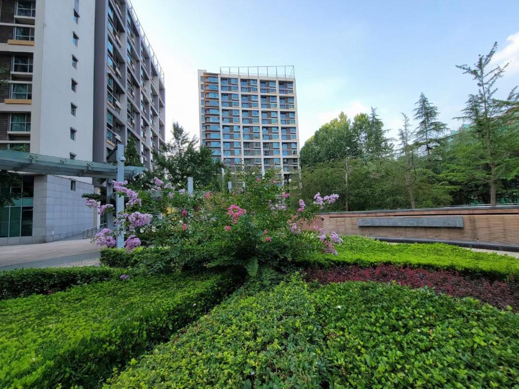 un giardino fiorito e un edificio in sottofondo di Beijing Yasmine Seasons Park Apartment Hotel a Pechino