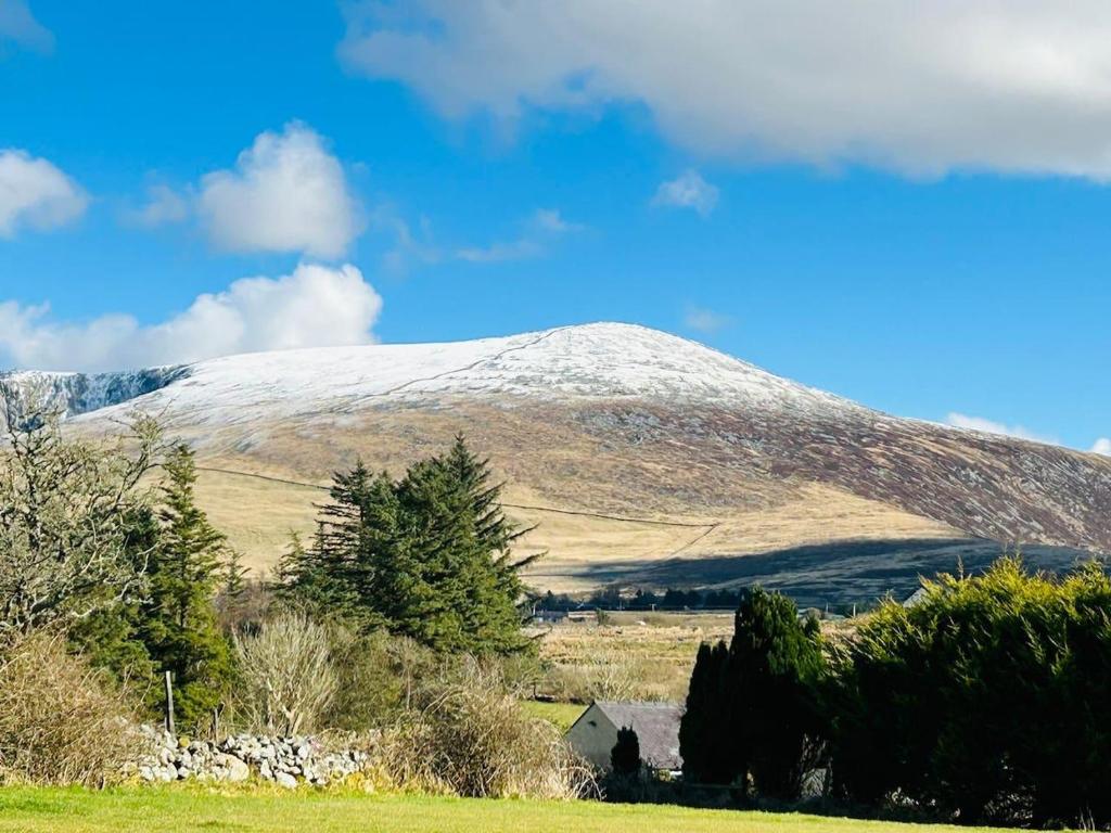 einen schneebedeckten Berg inmitten eines Feldes in der Unterkunft The Old Stables - a gem surrounded by mountains! in Caernarfon