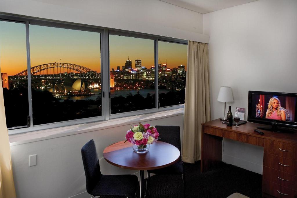 Cette chambre d'hôtel dispose d'un bureau et d'une table avec des fleurs. dans l'établissement Macleay Hotel, à Sydney