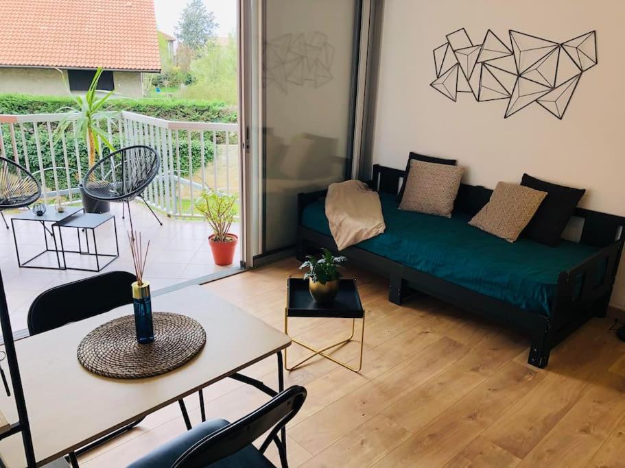 een woonkamer met een groene bank en een tafel bij Studio Moderne, Terrasse et Parking in Romans-sur-Isère