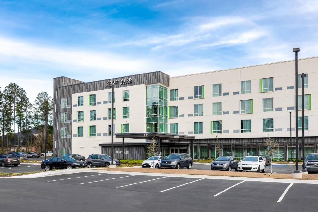 Courtyard by Marriott Savannah Airport في سافانا: مبنى مكتب فيه سيارات تقف في موقف للسيارات