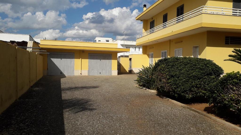 Maison jaune et blanche avec allée dans l'établissement Casa sole e luna, à Porto Cesareo