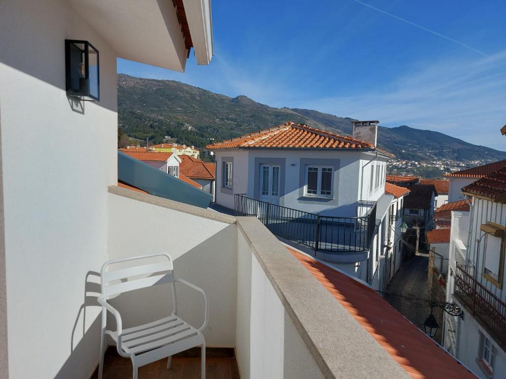 una silla blanca sentada en el balcón de un edificio en Ritta´s House - Covilhã, en Covilhã