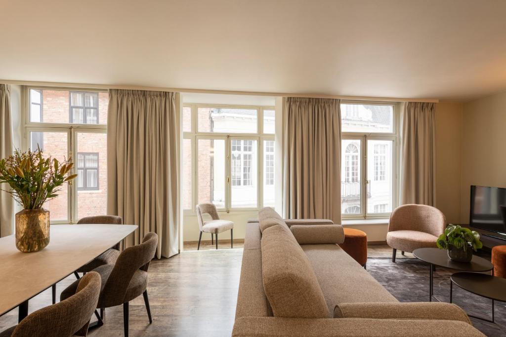 uma sala de estar com um sofá, cadeiras e janelas em Dukes' Apartments Grand Place - by Dukes' Hotel Collection em Bruges