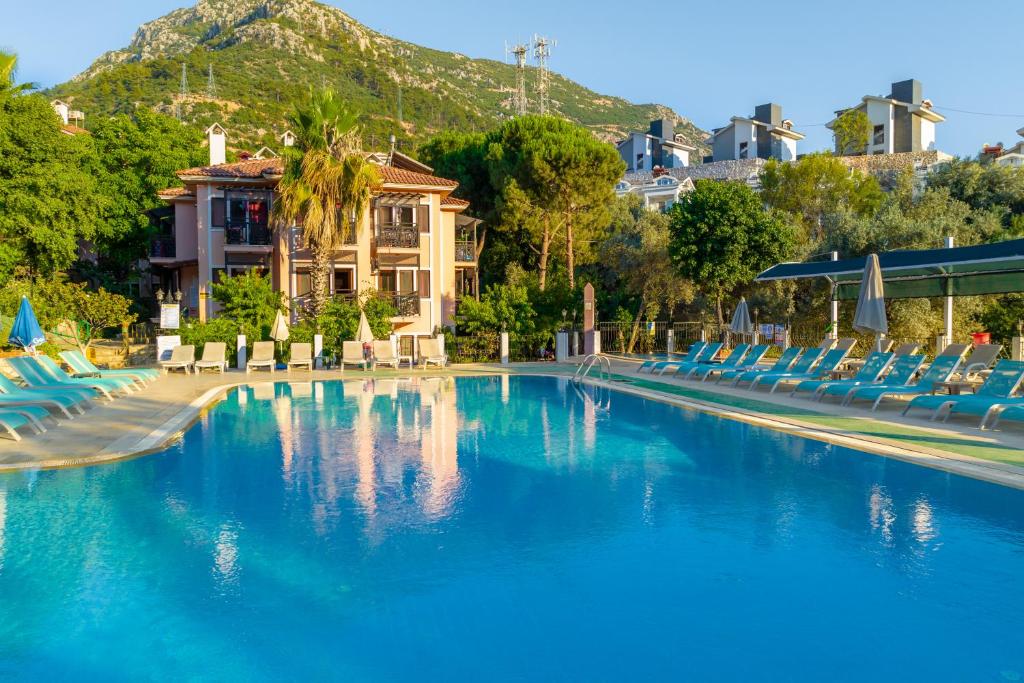 une piscine avec des chaises bleues et une montagne dans l'établissement Club Pink Palace Hotel, à Ölüdeniz