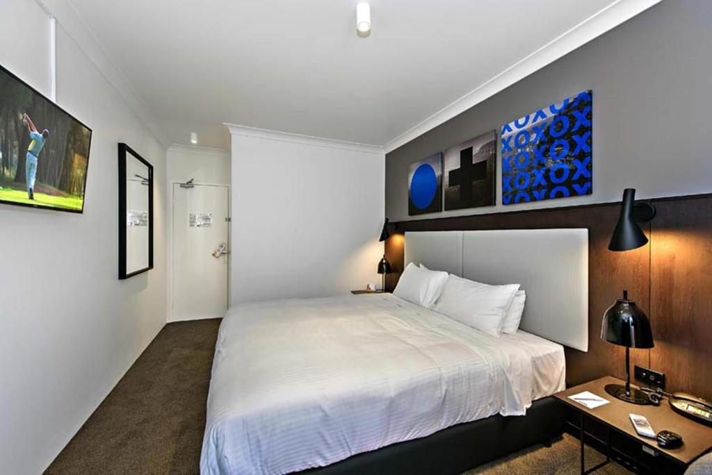 een slaapkamer met een groot wit bed en een bureau bij Silkari Urban CKS Sydney Airport Hotel in Sydney