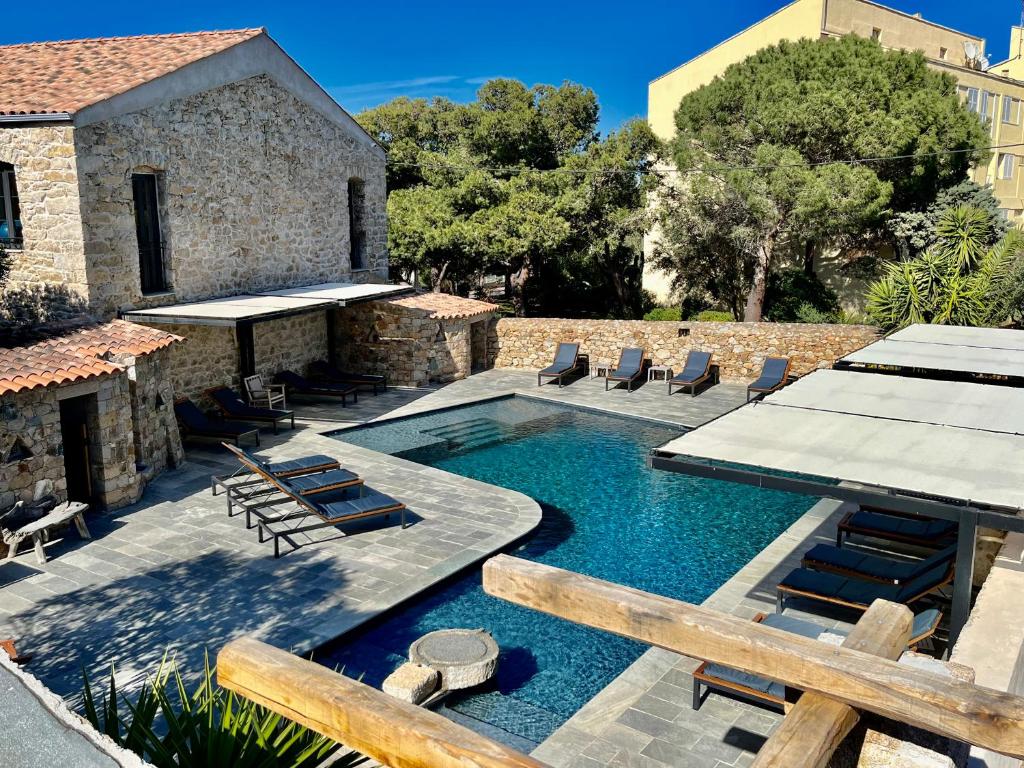 una piscina con sedie e un edificio di Hôtel Casa Rossa & Spa a LʼÎle-Rousse