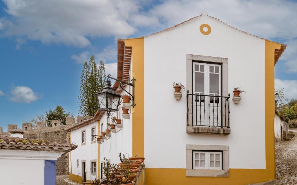 een wit en geel huis met een balkon bij Casa de S. Thiago de Obidos in Óbidos