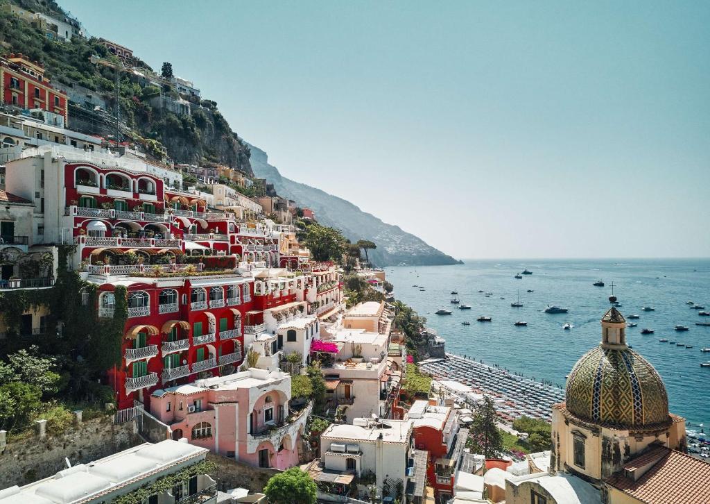 eine Gruppe von Gebäuden auf einem Hügel neben dem Meer in der Unterkunft Le Sirenuse in Positano