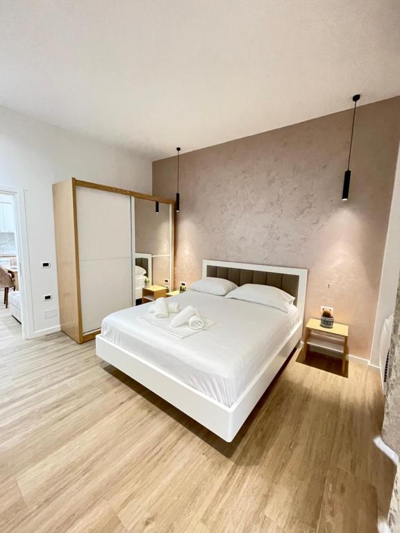 una camera da letto con un grande letto bianco e pavimenti in legno di Arial Trinity Suites a Vlorë