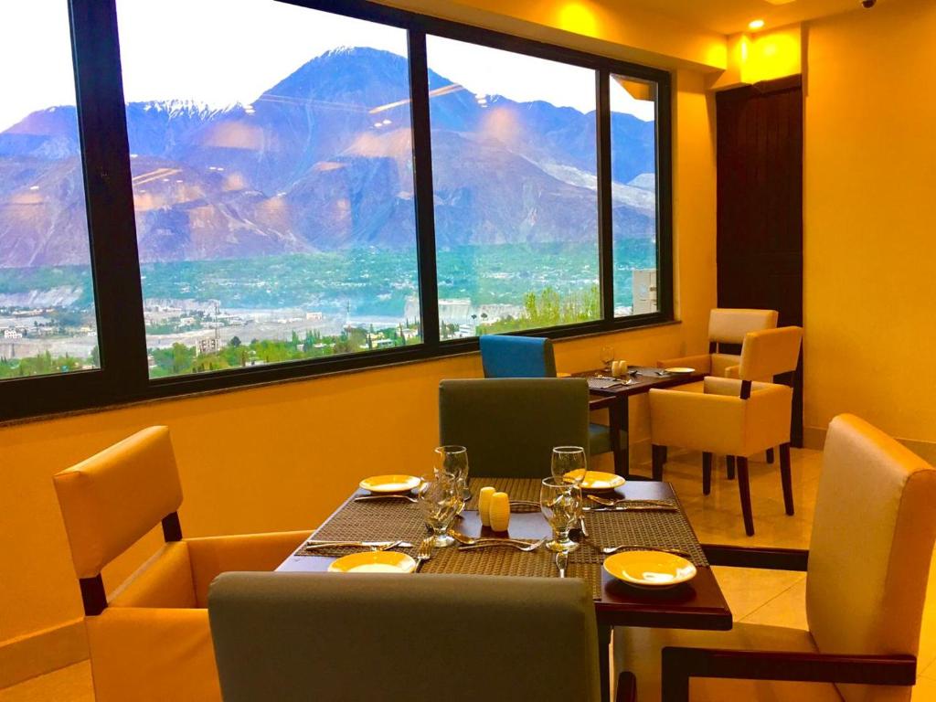 a restaurant with a table and chairs and a large window at Avari Xpress Gilgit in Gilgit