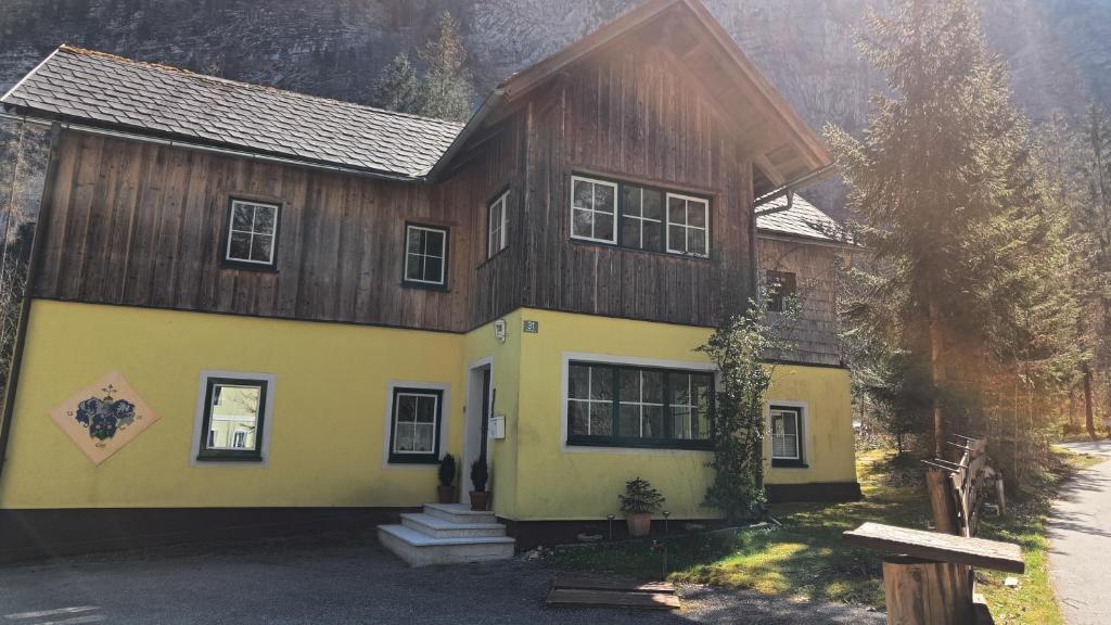 une maison avec un toit en bois et un jaune dans l'établissement Haus Waldbach, à Hallstatt