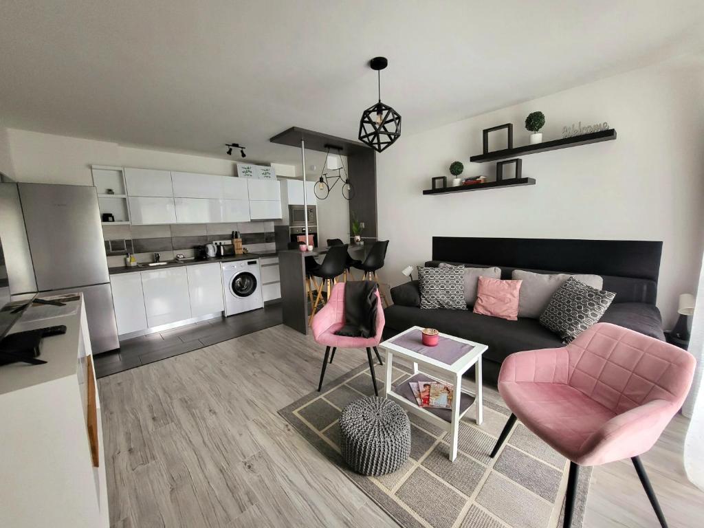 een woonkamer met een bank en roze stoelen bij Tisza River Apartman in Szeged