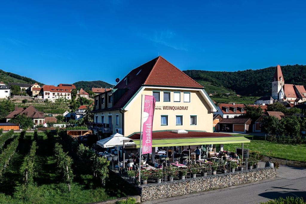 een gebouw met tafels en parasols ervoor bij Hotel Garni Weinquadrat in Weissenkirchen in der Wachau