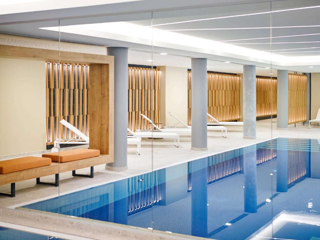 uma piscina com cadeiras e mesas num edifício em Novotel München City em Munique