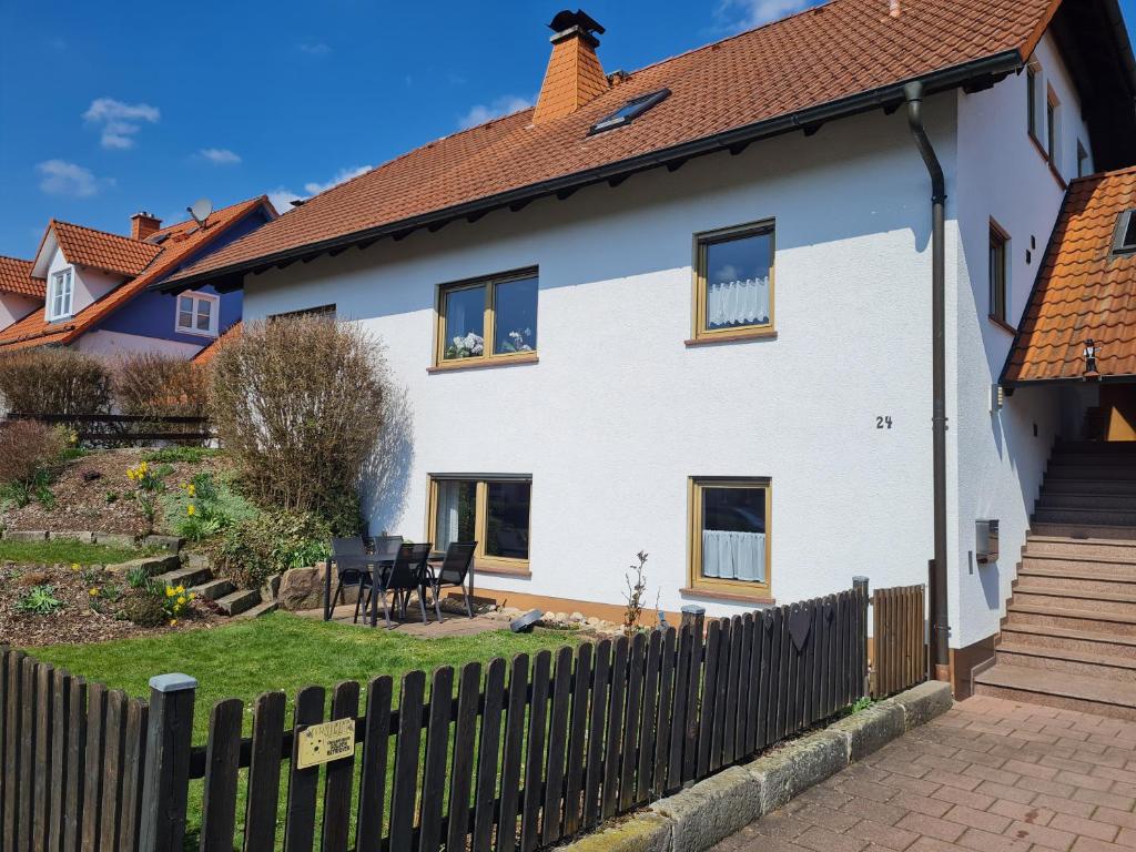 een wit huis met een houten hek bij Ferienwohnung Chrissi in Bischofsheim an der Rhön