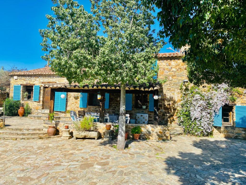 uma casa de pedra com uma árvore em frente em Casa La Rocita em Badajós