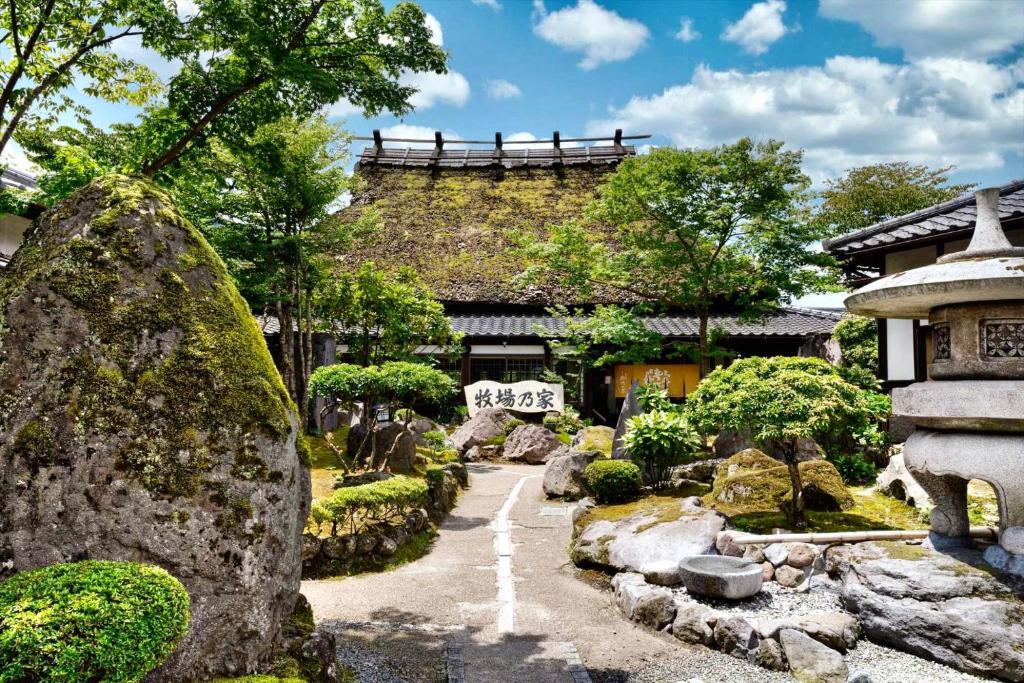 een tuin voor een gebouw met rotsen en bomen bij 由布の里 旅荘 牧場の家 Ryoso Makibanoie in Yufu