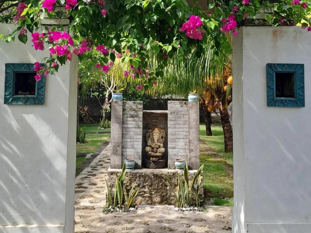 uma estátua no meio de um jardim com flores rosas em Hello Penida House em Nusa Penida