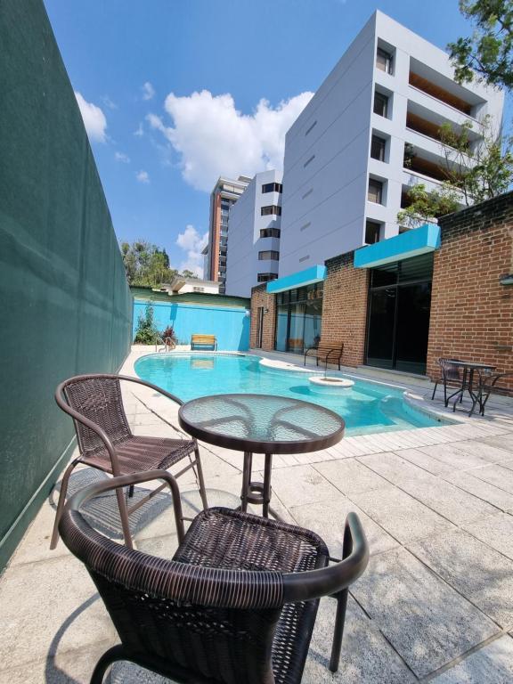 d'une terrasse avec une table et des chaises à côté de la piscine. dans l'établissement Central Hostel Zona 10, à Guatemala