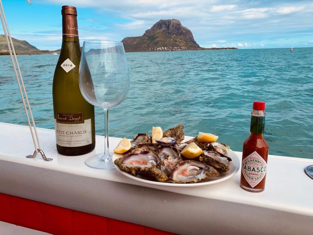 a plate of food and a glass of wine on a boat at Résidence au bout du Morne in Le Morne