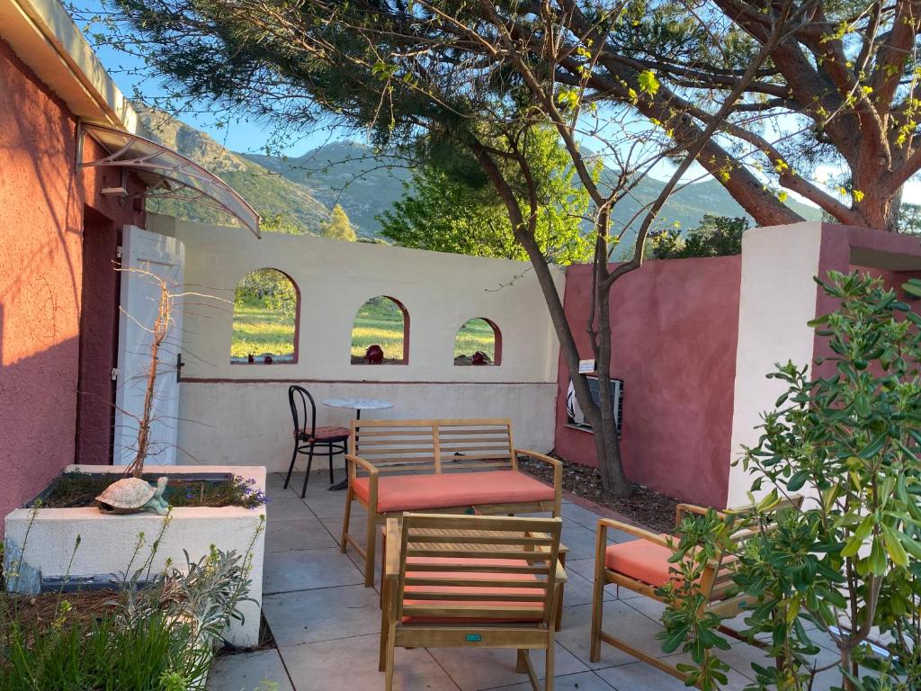 un patio con mesa, sillas y un árbol en Casa di Floumy, en Calvi